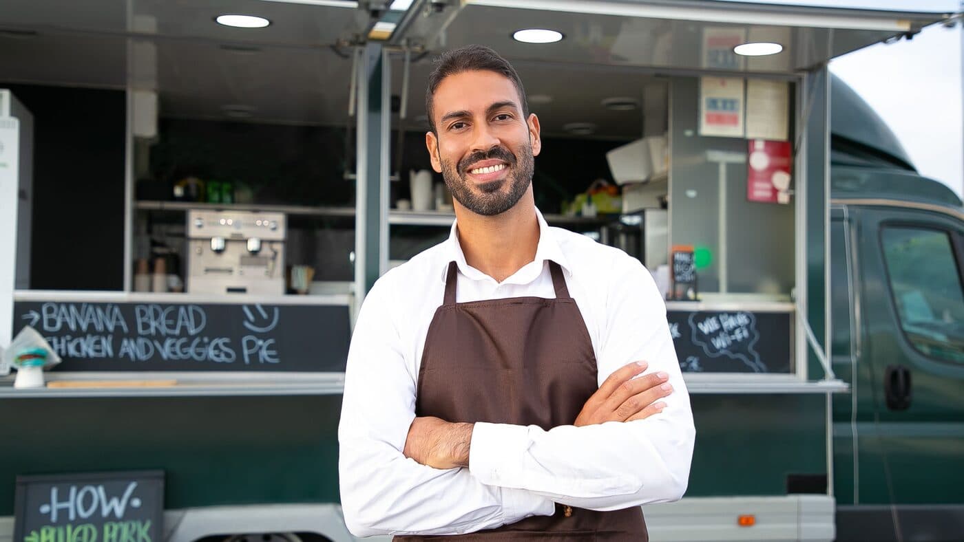 Food truck owner standing with his arms crossed in front of his truck